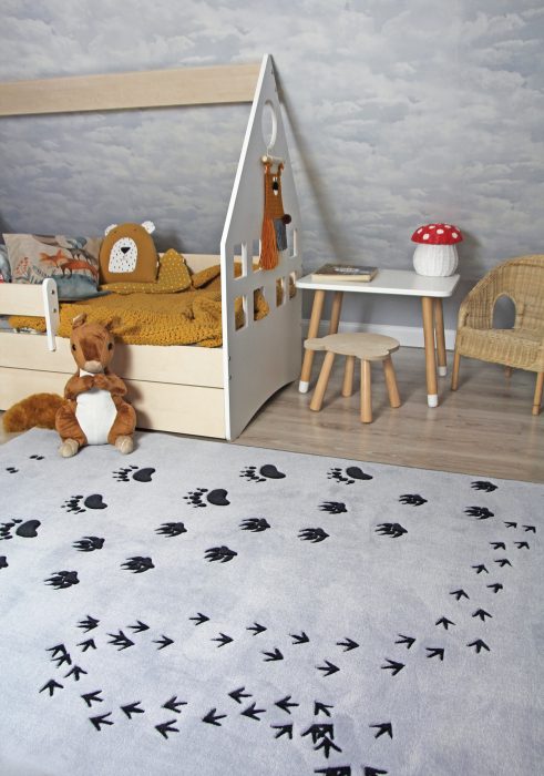 Dywan prostokątny szary leży na środku pokoju, obok stoi białe dziecięce łóżko w kształcie domku